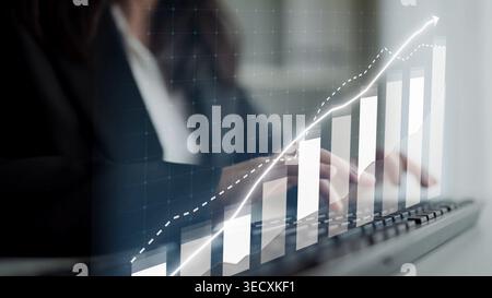 Professionnel de l'entreprise s'engage avec l'analyse des données sur un clavier tandis qu'un graphique de croissance ascendante superpose l'image, symbolisant le succès financier et Banque D'Images