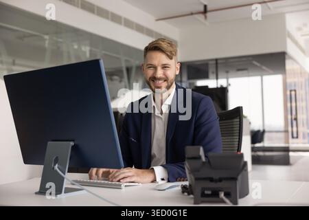 Portrait d'homme d'affaires confiant est assis au bureau dans le bureau moderne Banque D'Images
