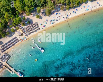 Vue aérienne de haut en bas d'une belle plage avec sports nautiques, parasols et les gens appréciant la mer turquoise, Koukounaries, île de Skiathos, Grèce Banque D'Images