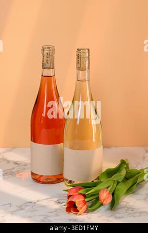 Les bouteilles de vin sont placées à côté des fleurs de tulipe sur une surface de table. Banque D'Images