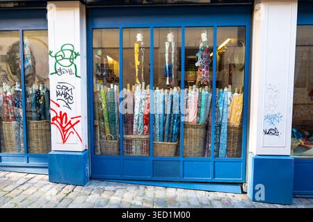 Vue sur la rue d'un magasin de tissus parisien avec des textiles vibrants en vitrine idéale pour la vente au détail de mode et les concepts de design Banque D'Images