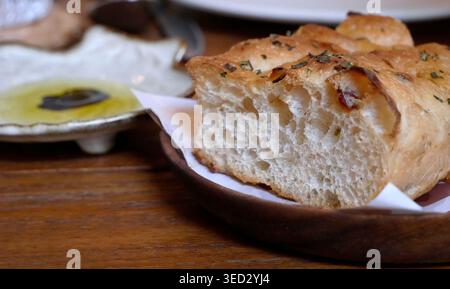 Tranches de pain artisanales italiennes Focaccia avec croûte croustillante dorée et texture aérée douce. Le pain assaisonné avec du sel de mer et des herbes séchées de romarin, Ser Banque D'Images
