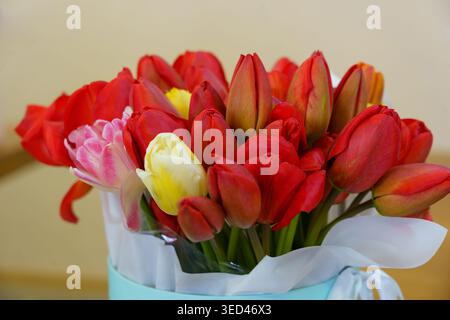 Les fleurs fraîches sont placées dans un vase sur une table, montrant des couleurs vibrantes et divers types. Le réglage semble chaleureux et invitant. Banque D'Images