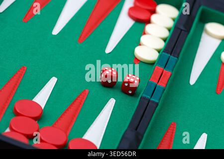 vue en grand angle d'un plateau de backgammon avec deux dés et plusieurs pions positionnés sur une surface de feutre vert avec des points triangulaires. Banque D'Images