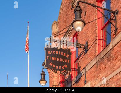 Ypsilanti, États-Unis - 12 février 2026 : extérieur du bâtiment en brique avec panneau suspendu lisant michigan Firehouse Museum, lampadaires vintage et drapeau américain Banque D'Images