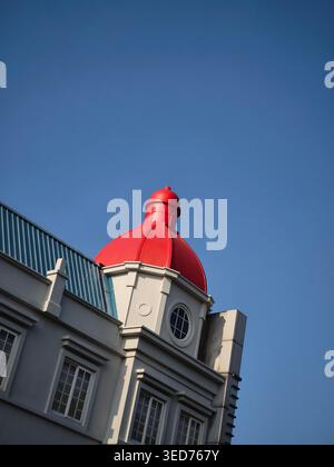 Un bâtiment moderne avec un dôme rouge saisissant se dresse sous un ciel bleu clair, présentant des lignes architecturales épurées et un design élégant de style européen. Banque D'Images