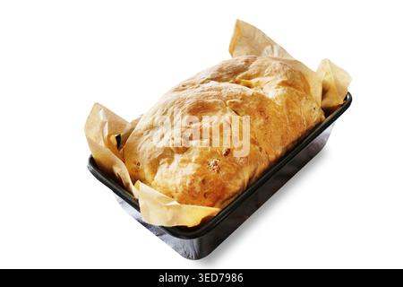 Pain artisanal fraîchement cuit dans un moule recouvert de papier parchemin, découpé sur fond blanc. Banque D'Images
