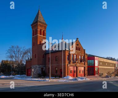 Ypsilanti, États-Unis - 12 février 2026 : caserne de pompiers historique en briques rouges avec une grande tour et une annexe moderne, scène de rue d'hiver sous un ciel bleu clair. Banque D'Images