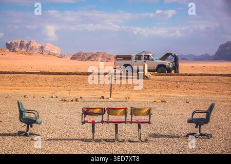 Moyen-Orient, Jordanie, désert de Wadi Rum, sièges vides sur le bord d'une route, en arrière-plan, un bédouin tombe en panne et soulève le capot. Banque D'Images