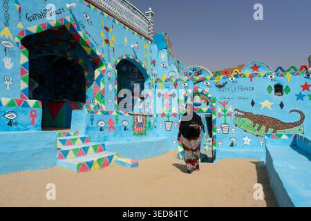 Egypte, Assouan, Gharb Sohail, Une femme dans sa maison décorée de peintures de crocodiles Banque D'Images