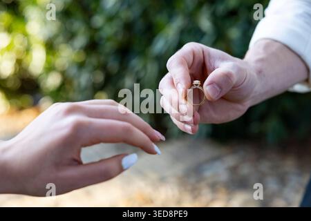 Homme mettant la bague de fiançailles sur son doigt comme fiancée pour être mariée Banque D'Images
