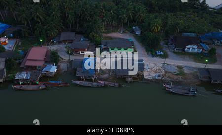 Vue aérienne des maisons de village traditionnelles le long de la rivière chumphon, thaïlande au crépuscule Banque D'Images