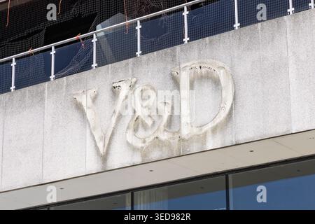 Zeist, pays-Bas, 28 avril 2026. Gros plan du logo emblématique mais altéré du grand magasin V&d sur une façade en béton texturé sous une rampe en verre Banque D'Images