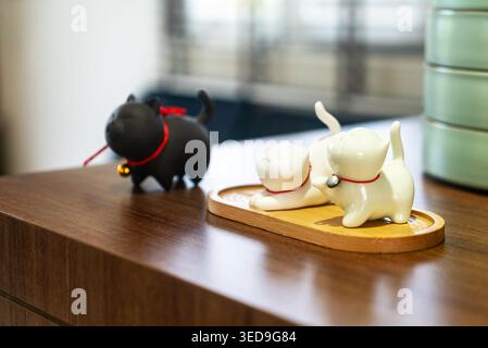 Les figurines décoratives en céramique d'un chat et d'un chien placées sur une surface en bois offrent une touche charmante et ludique aux espaces intérieurs, parfaits pour la décoration intérieure Banque D'Images