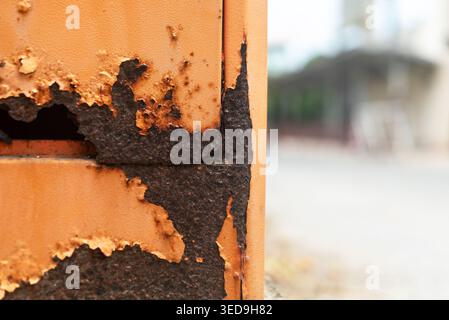 Une photographie en gros plan capture un mur de briques vieilli avec de la peinture écaillée et de la rouille, mettant en valeur la texture et la surface altérée causées par l'extérieur prolongé Banque D'Images