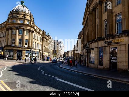 Scène de rue historique à Newcastle upon Tyne avec architecture classique, piétons et boutiques par une journée ensoleillée Banque D'Images