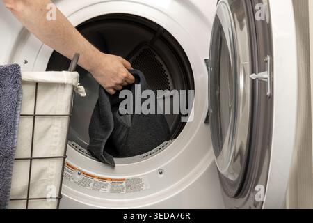 Gros plan du chargement des chiffons dans le tambour du lave-linge Banque D'Images