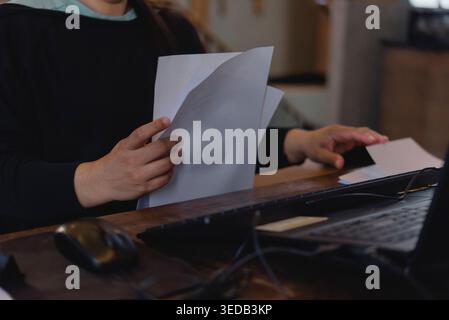 Femme d'affaires tenant et vérifiant la pile de documents au bureau. Employé féminin examinant les documents, les rapports ou le contrat près de l'ordinateur portable. Administrateur Banque D'Images