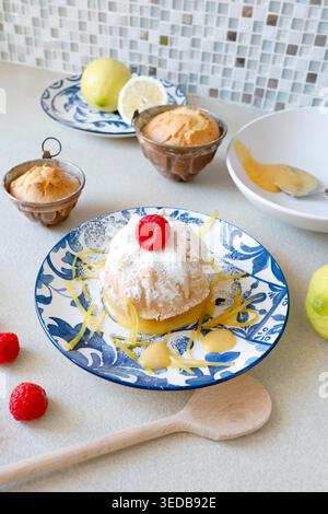 Mini gâteau citron Bundt avec Curd et framboises. La tendance de la pâtisserie méditerranéenne authentique met l'accent sur les ingrédients biologiques naturels et les agrumes vibrants Banque D'Images