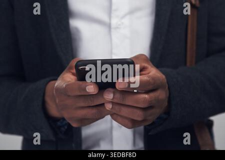 Mains, téléphone et dactylographie avec homme d'affaires en studio pour la communication, le réseautage ou la recherche. App, médias sociaux et SMS avec l'employé au travail Banque D'Images