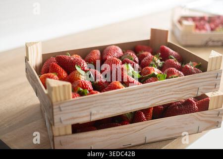 Fraises fraîches sur des boîtes en bois sur une table en bois Banque D'Images