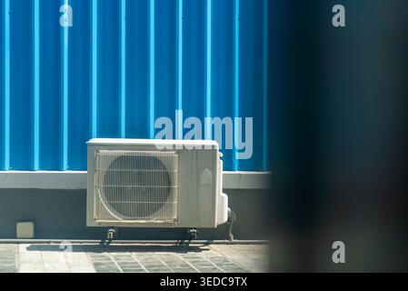 Une unité de climatisation positionnée contre un mur bleu frappant. Cette image illustre la technologie moderne de contrôle de la température, essentielle pour le confort de la maison A. Banque D'Images