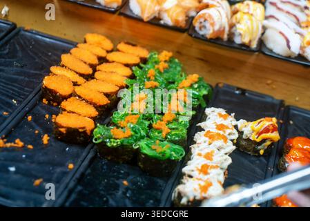 Un assortiment vibrant de sushis aux textures et ingrédients colorés, parfait pour capturer l'essence de la cuisine japonaise et culinaire Banque D'Images