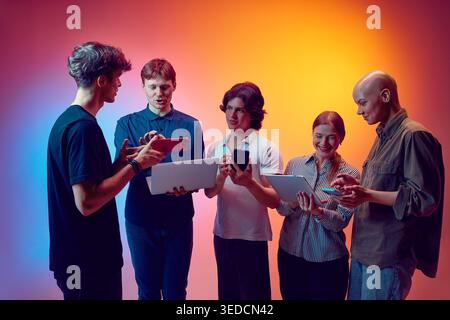 Jeune équipe discutant des smartphones et des tablettes pour la stratégie de produit numérique en studio. Banque D'Images