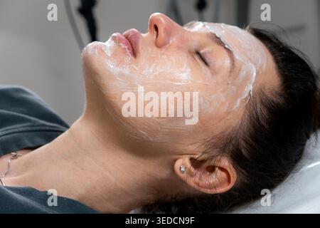 Gros plan recadré d'un cosméticienne méconnaissable effectuant une procédure de cosmétologie de photo rajeunissement pour femme dans une clinique de beauté moderne. Concept de Banque D'Images