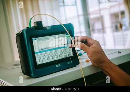 Gros plan de la main d'une personne interagissant avec un dispositif de saisie de données portable, présentant un écran moderne dans un espace de travail lumineux, illustrant la technologie Banque D'Images