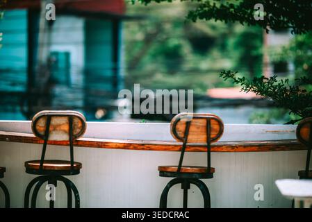 Une scène sereine avec des tabourets de bar rustiques en bois disposés à l'extérieur. L'espace vide invite à la détente et au plaisir, idéal pour des rassemblements confortables dans un Banque D'Images