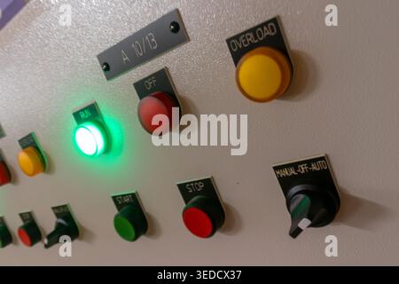 Vue rapprochée d'un panneau de commande avec divers boutons et indicateurs de différentes couleurs, présentant les éléments opérationnels des machines et de la technologie Banque D'Images
