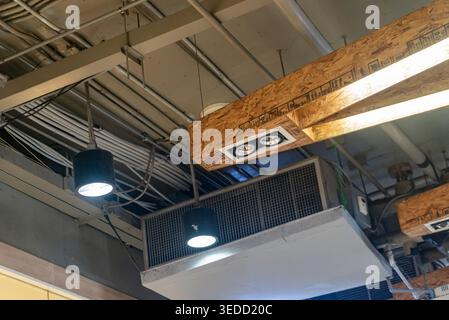 Une vue détaillée d'un plafond industriel avec des luminaires modernes, des conduits de ventilation et des câbles exposés dans un espace de travail contemporain environ Banque D'Images