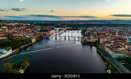Vue aérienne du pont Charles enjambant la rivière Vltava avec des toits rouges historiques et l'horizon de la ville pendant le coucher du soleil Prague, Prague, Tchéquie. Banque D'Images