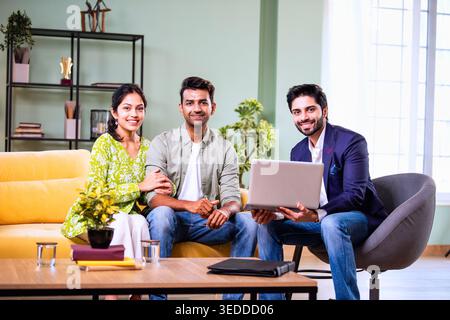 Couple indien discutant avec l'agent à la maison pendant la réunion d'investissement avec l'homme d'affaires examinant les documents financiers et les dossiers tout en étant assis sur le canapé dedans Banque D'Images