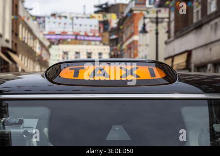 Gros plan d'un panneau de taxi jaune sur un taxi noir dans la ville Banque D'Images