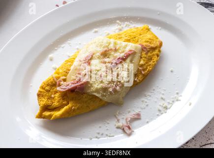 Vue de dessus d'une omelette farcie roulée avec du jambon et du fromage servi sur une assiette blanche dans un restaurant à Positano, Italie. Délicieux plat de petit déjeuner avec Go Banque D'Images