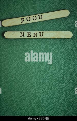 MENU ALIMENTAIRE à composition verticale sur bâtons en bois sur une surface en cuir vert. Copier l'espace Banque D'Images