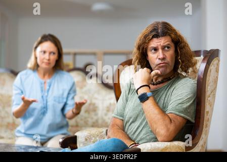Homme et femme d'âge moyen établissant des relations entre eux assis sur le canapé Banque D'Images