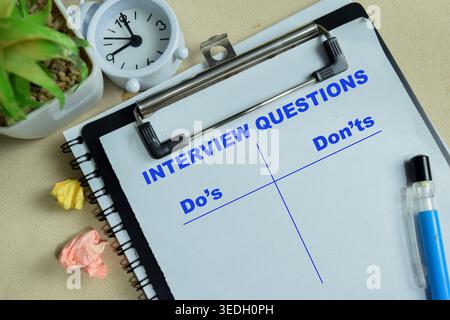 Concept des questions d'entrevue à faire et à ne pas écrire sur le presse-papiers isolé sur la table en bois. Banque D'Images