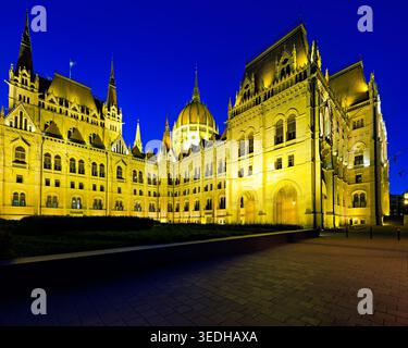 Coucher de soleil sur le bâtiment du Parlement à Budapest montre la structure illuminée. Les lumières reflètent la beauté de la ville à la tombée de la nuit. Banque D'Images