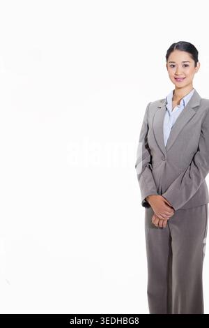 Femme asiatique adulte posant en studio portant un costume gris clair et un chemisier bleu clair, espace copie. Headshot, professionnel, entreprise, minimaliste, propre, donc Banque D'Images