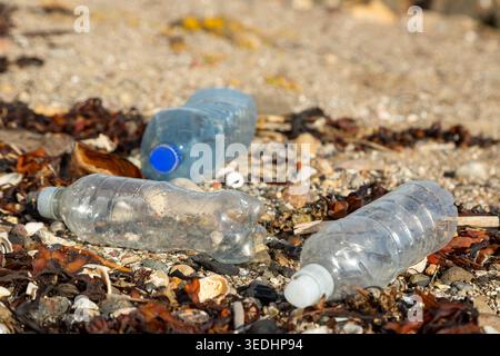 Déchets de bouteilles d'eau en plastique sur la plage de sable Banque D'Images