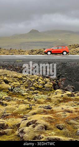 Voiture rouge sur la route panoramique à travers le paysage volcanique de Mossy Banque D'Images