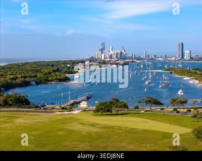 Vue aérienne pittoresque du paysage urbain de la Gold Coast, avec de nombreux bateaux ancrés sur des eaux bleues et un parc verdoyant sous un ciel dégagé. Banque D'Images