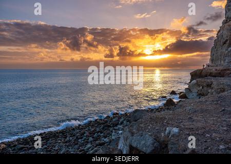 Coucher de soleil vue sur la plage de pierre vide et la côte rocheuse à l'ouest de Puerto de Mogan Banque D'Images