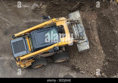 Le bulldozer ou le chargeur se déplace et nivele le sol sur le chantier de construction. EQUIPEMENT lourd de construction pour travaux de terrassement. Engin de terrassement. Un patin Banque D'Images