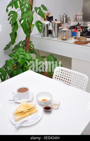 un petit-déjeuner typique de style kopitiam se compose de kopi susu ou café au lait sucré, de toasts kaya et d'œufs durs, servis dans une table blanche Banque D'Images