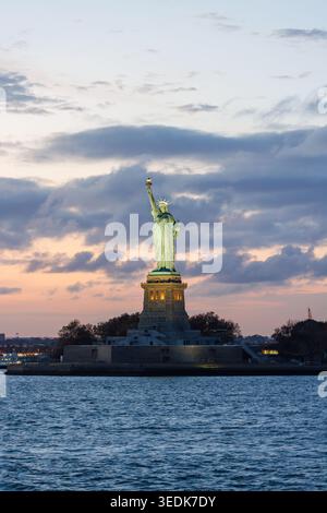 Statue de la liberté au coucher du soleil avec un ciel spectaculaire et une lumière dorée chaude se reflétant sur le monument Banque D'Images