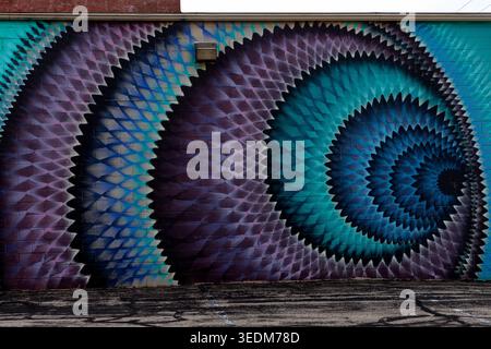 Dubuque, Iowa, États-Unis - 25 avril 2026 : murale géométrique abstraite avec des motifs en spirale bleus et violets peints sur un mur de bâtiment dans le centre-ville de Dubuque Banque D'Images